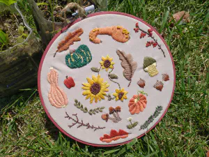 an embroidered hoop depicting gourds and fall leaves