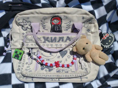 a bag covered in black doodles with many keychains and a patch