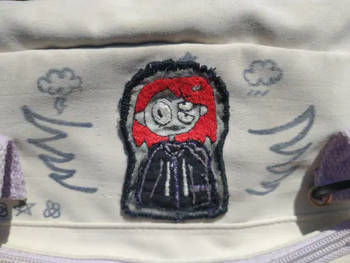 an embroidered patch depicting a character with red hair named belts